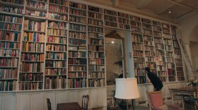 Adam Weinberger examines a bookshelf in the documentary <em>The Booksellers</em>.