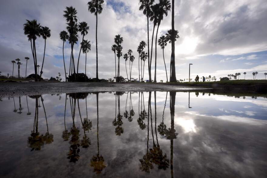 Two people walk along Mission Bay during a break in the rain in San Diego. California's current rainy season got off to a slow start but has rebounded with recent storms. (Gregory Bull/AP)