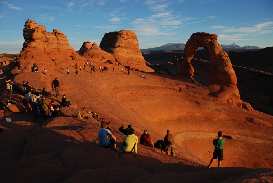 Park visitors gather to watch the sunset at Delicate Arch in Arches National Park