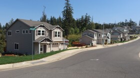 An August 3, 2026 photo shows the two homes sitting on either side of a vacant lot. The home in between the two was more extensively damaged in the landslide and was removed.