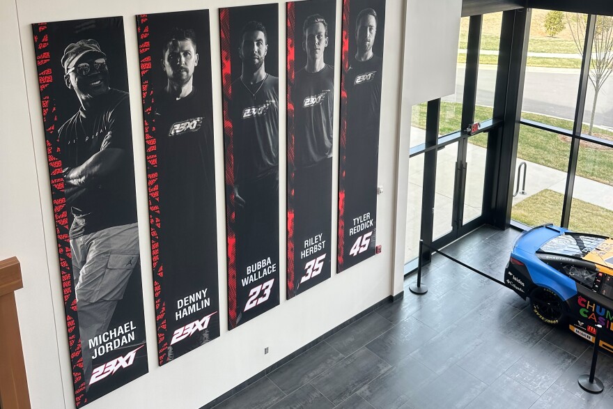 A banner, showing co-owners Michael Jordan and Denny Hamlin, as well as drivers Bubba Wallace, Corey Heim and Tyler Reddick, hangs in the lobby at Airspeed, the headquarters of 23XI Racing, Tuesday, Feb. 24, 2026 in Huntersville, N.C. (AP Photo/Jenna Fryer)