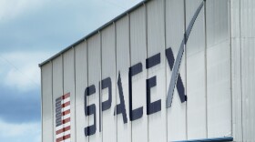 A white building side that says Space X in big bold dark blue letters. There's an american flag painted on the building, too. 