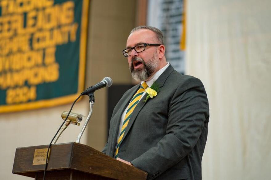 A bearded white man speaks at a podium