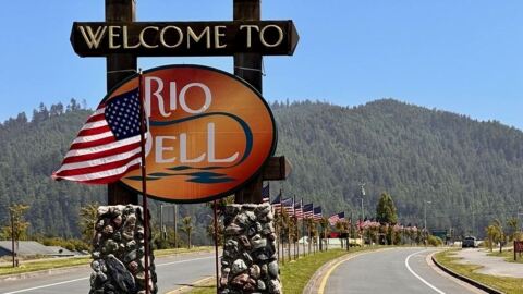 Welcome sign at the entrance to Rio Dell, California, with trees and greenery in the background.
