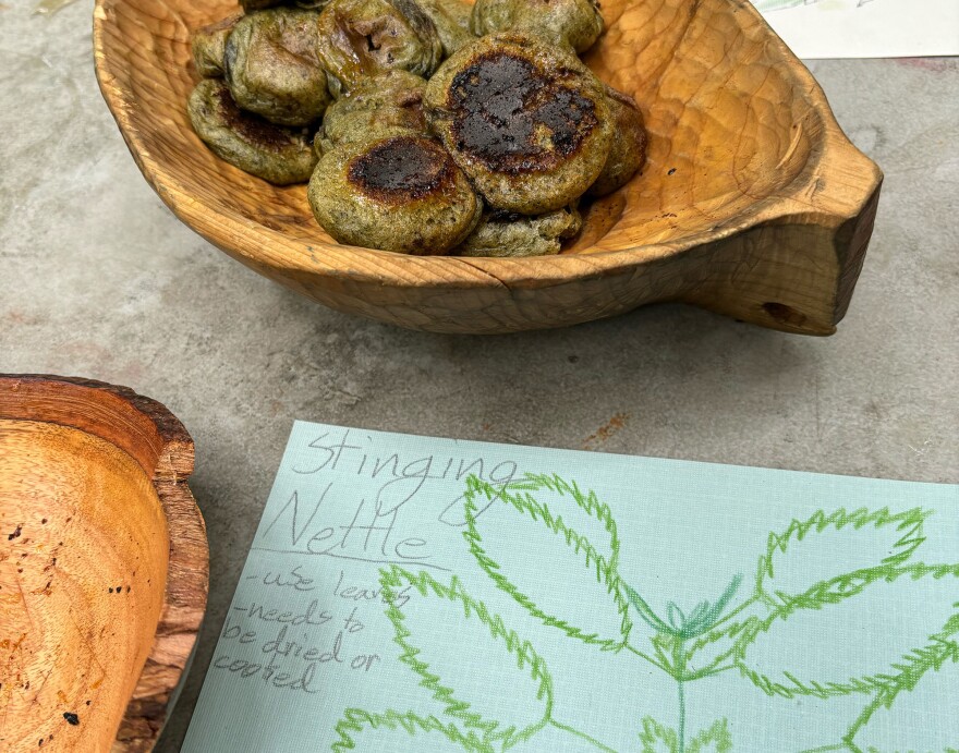 round greenish and brown cooked pillows in a wooden bowl with a drawing and description of stinging nettles