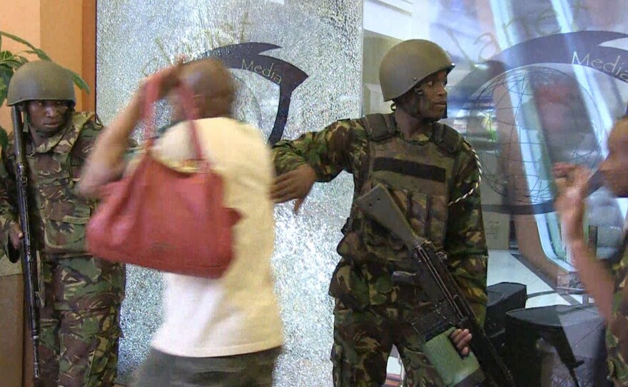 Kenyan forces help civilians flee the building on Saturday. The attackers remained inside the mall throughout the night.