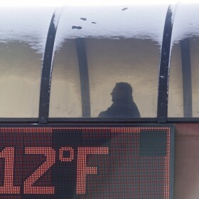 A thermometer shows the temperature as a man walks to a parking garage during the cold winter weather.
