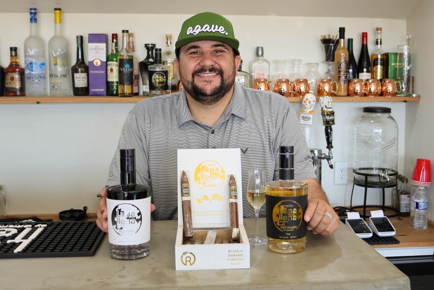 Omar Ramirez poses with his cigar and tequila products. The tequila by the name Luna Llena, comes from agave grown and distilled in Mexico.