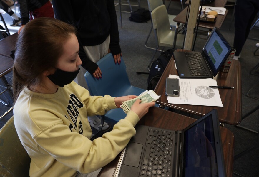 Olivia Bartek, counts the money she earned working at a pizza shop to pay for an application to a college . The Hilton High School senior was taking the Personal Money Management class.