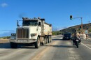 A traffic light in West Maui signals vehicle flow as dump trucks filled with fire debris leave Olowalu.