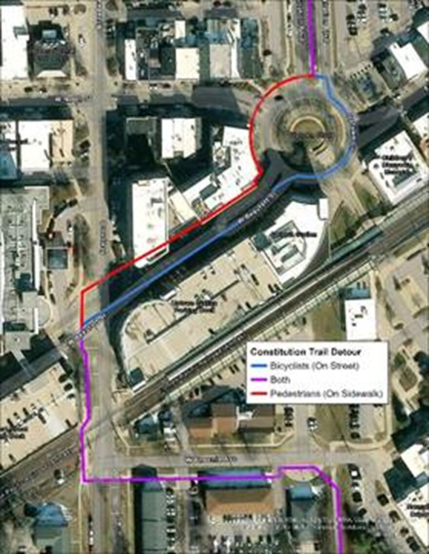 An overhead view of a map of an urban area that includes purple, red and blue lines to indicate road detours for pedestrians and cyclists