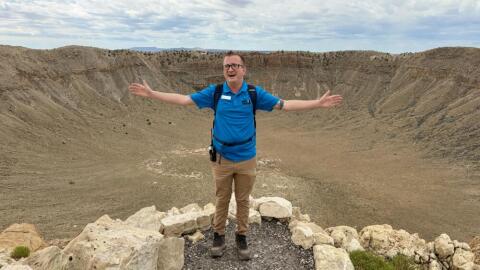 Hikers can walk to the bottom of Meteor Crater in Northern Arizona. Guide Tyler Johnson speaks to a group at the top of the mile-wide hole that was formed 50,000 years ago when a meteorite struck the earth. (Peter O’Dowd/Here & Now)