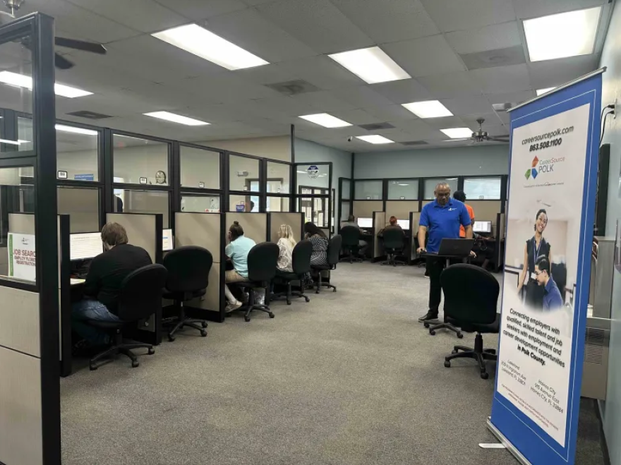 Group of people in an office space working in at computers at cubicles 