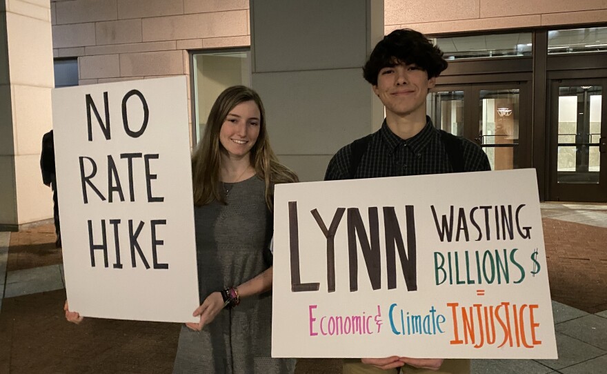 Kate Lewin and Lucas Blanco protest Duke Energy outside the Mecklenburg County Courthouse ahead of the company's rate increase public hearing.