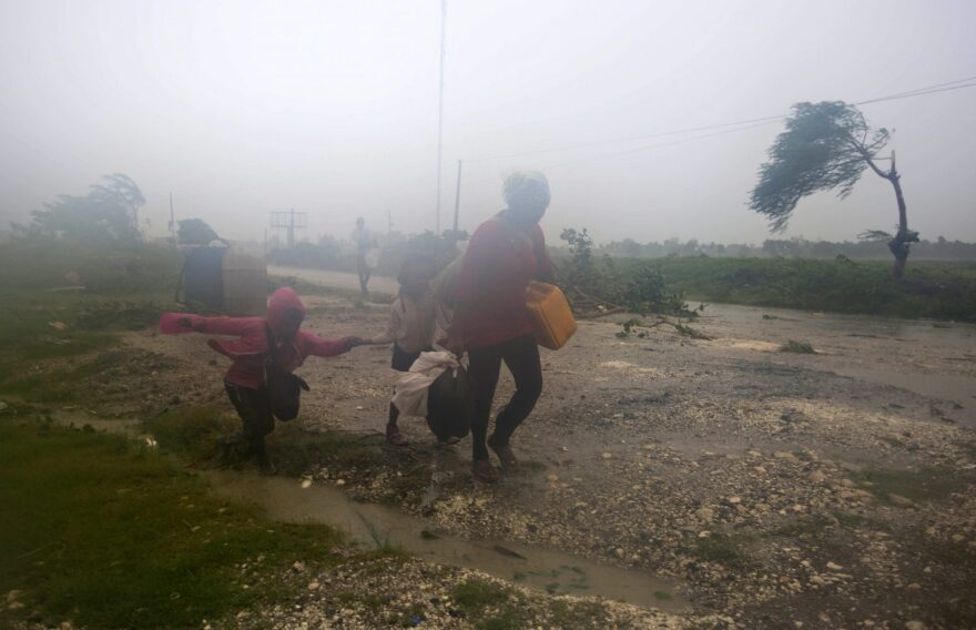 Residents head to a shelter in Leogane, Haiti, Tuesday, Oct. 4, 2016. Matthew slammed into Haiti's southwestern tip with howling, 145 mph winds Tuesday, tearing off roofs in the poor and largely rural area, uprooting trees and leaving rivers bloated and choked with debris. (AP Photo/Dieu Nalio Chery)