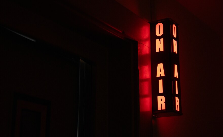 "ON AIR" yellow studio lighted sign on a dark black background at BPR studios