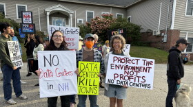 Three people pose holding signs against data centers.