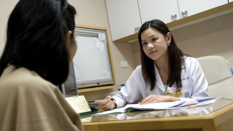 A female doctor looks over a chart with a patient.