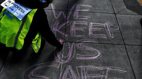 Crouched, Alice draws large letters on the sidewalk with chalk.