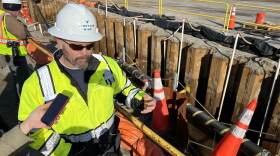 Ian Campbell of Vineyard Wind explains work done Tuesday to pull electrical cable from near-shore waters through a conduit under Covell's Beach in Barnstable. At right is the cable, in a trench held open by a temporary retaining wall. The wall and metal stanchions holding the cable will be removed before the trench is filled. Campbell is the company's senior environmental permit and compliance manager.