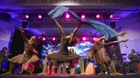 People in dresses dance on a stage.