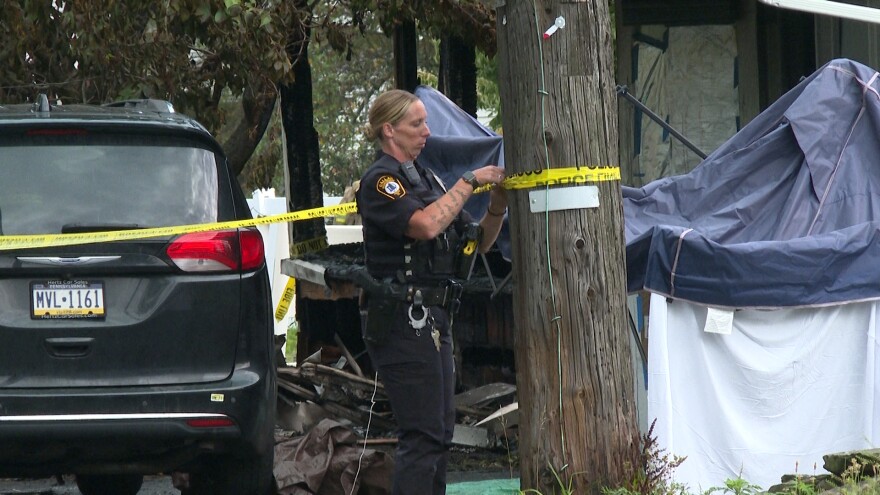 A police officer ties caution tape to a pole at the scene of a fatal house fire in Shavertown, Kingston Twp., Luzerne County on Wednesday, Aug. 5, 2026.