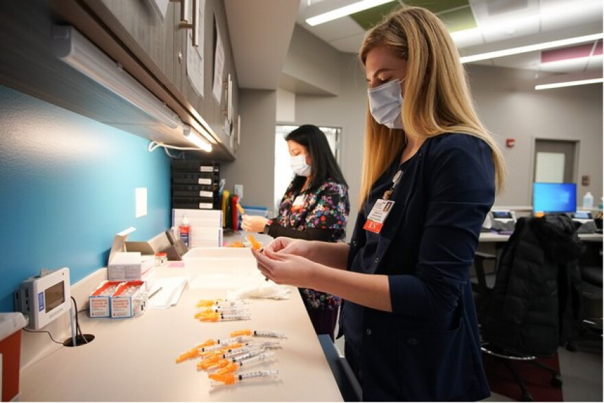 Nurses prepare the first dose of the Moderna COVID-19 vaccine at the OSF vaccination clinic in Peoria.  OSF administers around 500 vaccines at the site per day.