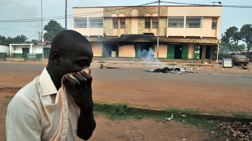 A man covers his nose as he walks past a charred body on Feb. 9 in central Bangui.