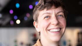 Person in a brown shirt smiling in an indoor space