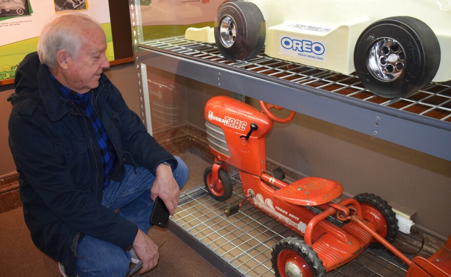 Man bending down to look at a mini model of a riding tractor