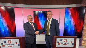 Two political candidates shake hands before a political debate. One on the left is shorter than the man on the right.