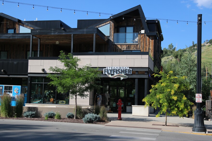 A large brown building with a sign that reads "Steamboat Flyfisher" with a fish underneath it.