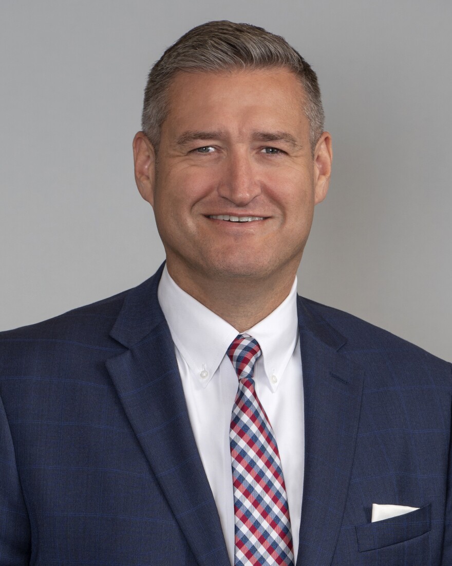 A man in a suits smiles at the camera