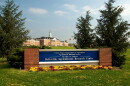 A blue sign reading "Beltsville Agricultural Research Center" sits at the entrance of a research campus, with a large building in the background