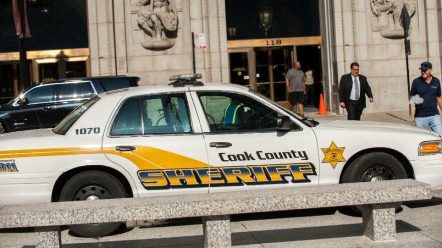 A mid to late 2000's Crown Victoria police interceptor with Cook County insignia sits in front of a building in downtown Chicago