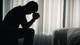 Silhouette depressed man sadly sitting on the bed in the bedroom, depression concept