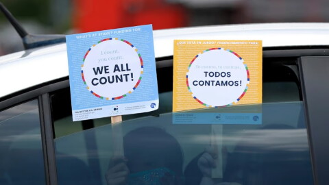FILE: Two young children hold signs through the car window that make reference to the 2020 U.S. Census as they wait in the car with their family at an outreach event in Dallas, June 25, 2020.