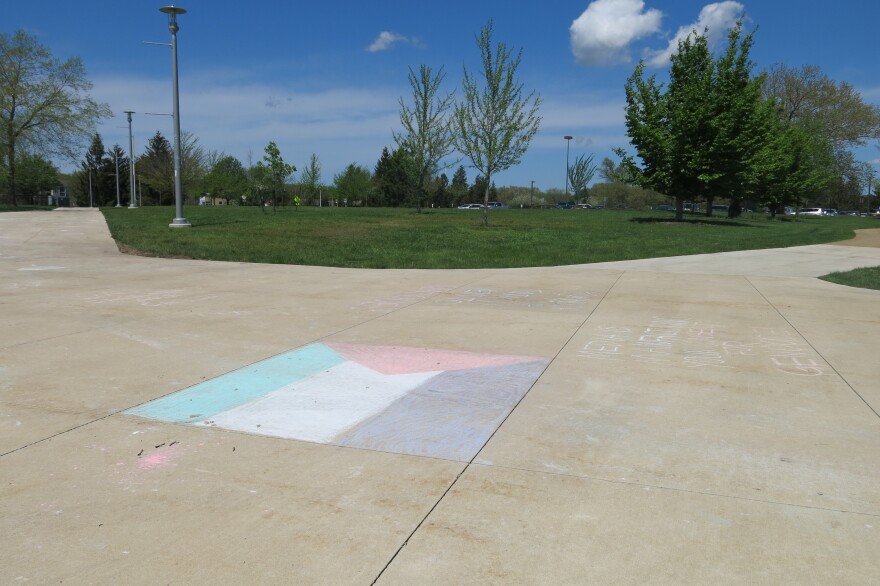 Palestinian flag drawn in chalk on the sidewalk in front of an empty lawn 