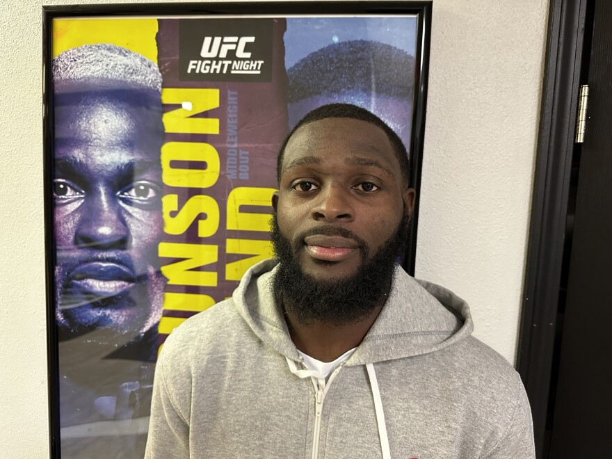 UFC bantamweight Montel Jackson stands in front of a fight poster at Pura Vida BJJ & MMA in Milwaukee. Jackson competed at UFC Fight Night: Brunson vs. Holland, defeating his opponent by TKO in the first round.