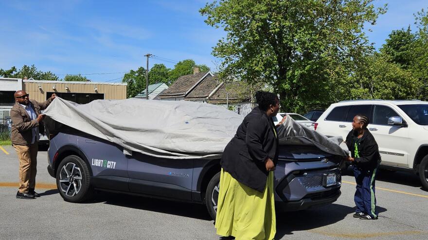 Members of Light City Carshare display one of the group's three electric vehicles.