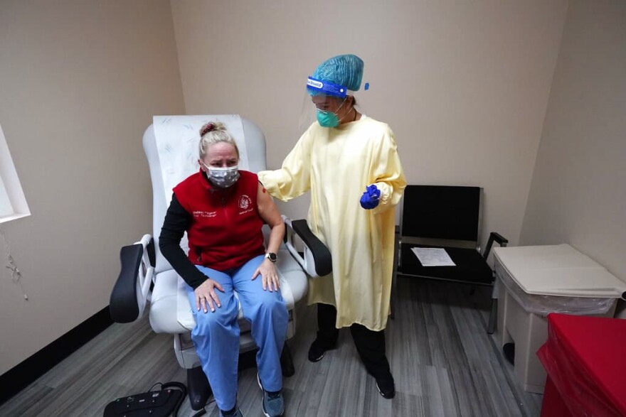 Medical worker Melissa Fitzgerald, left, begins to weep in an emotional response after receiving a COVID-19 vaccination from registered nurse Alyssa Lane Thursday, Dec. 17, 2020, on the Lummi Reservation, near Bellingham, Wash. (Elaine Thompson/AP Photo)