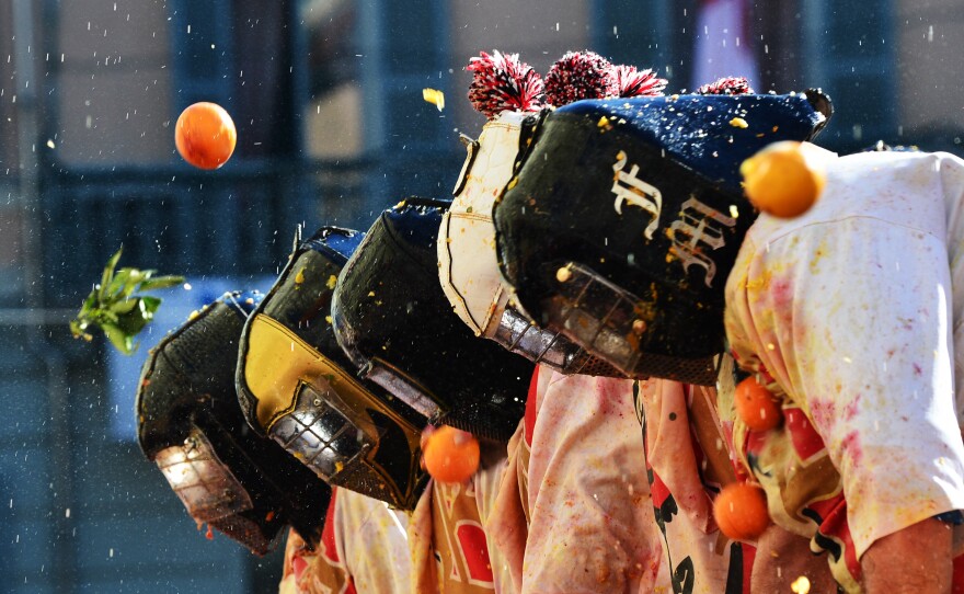 Men with helmets are hit by oranges during the traditional "battle of the oranges," held during the carnival in Ivrea, Italy. During the event, which marks the people's rebellion against tyrannical lords who ruled the town in the Middle Ages, revelers parading on floats represent guards of the tyrant, while those on foot are the townsfolk.