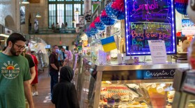  Customers browse a pastry stand at the West Side Market. Above, a sign advertises cannoli. 