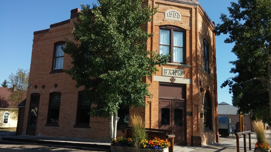 A two-story brick building on a street corner, with “1901” and “Bank” on the front of the building.
