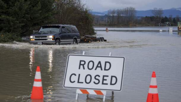 A driver manages to drive through flood waters from the Snohomish River in Snohomish, Washington, on Dec. 11, 2025. Tens of thousands of people were under evacuation orders Thursday in western North America, after days of heavy rain forced rivers to burst their banks. Storms have battered Washington state in the US and British Columbia over the Canadian border for several days, with rivers continuing to rise. (Jason Redmond / AFP via Getty Images)