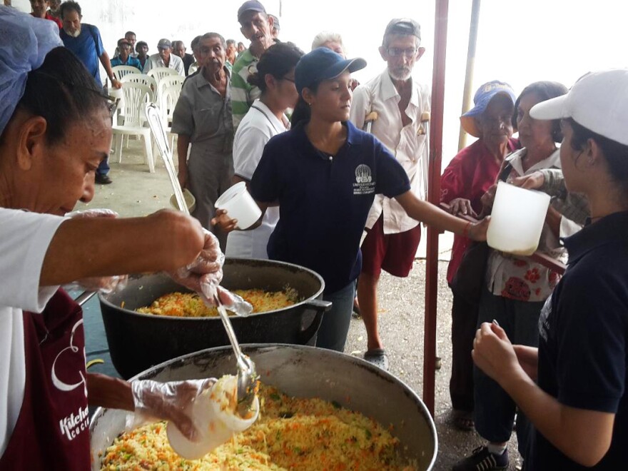 Men, women and children line up for free lunch at a soup kitchen in Maracaibo, Venezuela. The meal consists of a bottle of milk and a few scoops of rice mixed with eggs and vegetables.