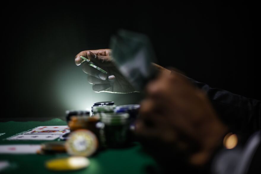 darkly lit, soft focus photo of person gambling, playing a card game such as black jack. 