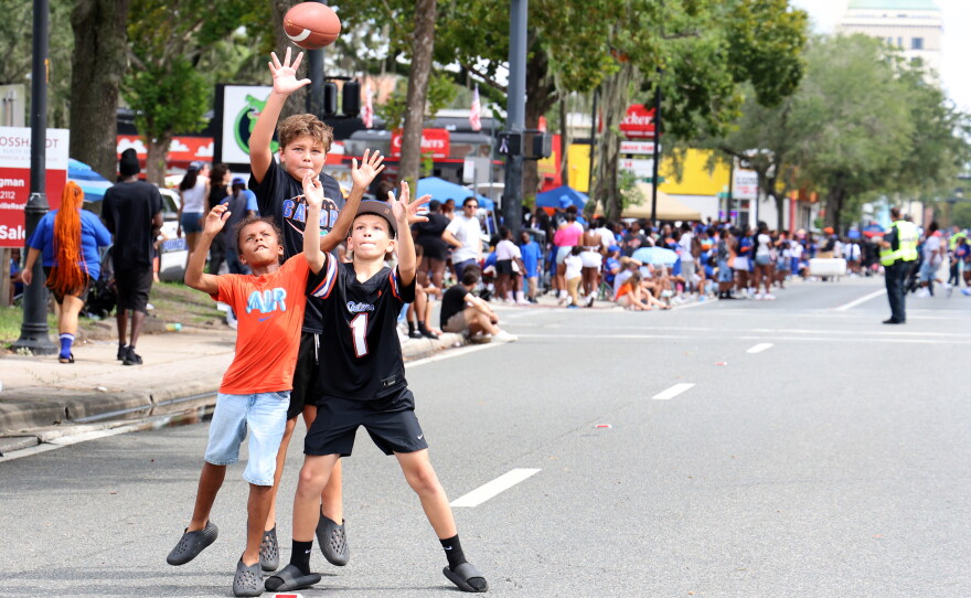 Children jump for a football before the start of the University of Florida Homecoming parade in Gainesville, Friday, Oct. 9, 2026. (Isabel Kraby/WUFT News)