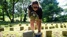 Sherill Baldwin holds a photo of reunited family members of Anna Horan next to her headstone in Blake Street Cemetery in New Haven on July 2, 2026.