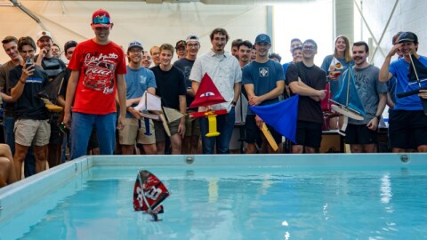 Engineering students sail their boats across a pool in the 35th Annual Wooden Shoe Regatta.